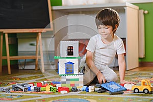 Children play with a toy designer on the floor of the children's room. Boy playing with colorful blocks