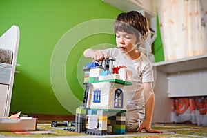 Children play with a toy designer on the floor of the children's room. Boy playing with colorful blocks