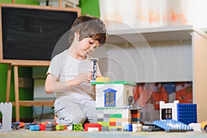 Children play with a toy designer on the floor of the children`s room. Boy playing with colorful blocks. Kindergarten educational