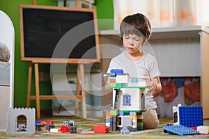 Children play with a toy designer on the floor of the children`s room. Boy playing with colorful blocks. Kindergarten educational