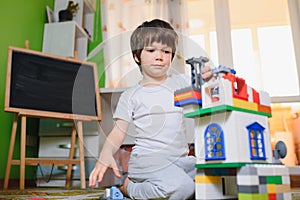 Children play with a toy designer on the floor of the children`s room. Boy playing with colorful blocks. Kindergarten educational