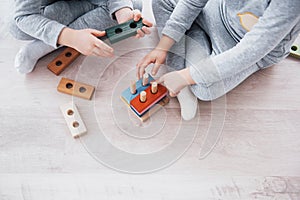 Children play with a toy designer on the floor of the children`s room. Two kids playing with colorful blocks