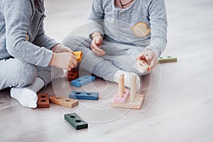 Children play with a toy designer on the floor of the children`s room. Two kids playing with colorful blocks