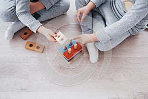 Children play with a toy designer on the floor of the children`s room. Two kids playing with colorful blocks