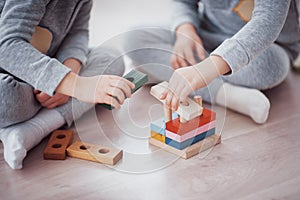 Children play with a toy designer on the floor of the children`s room. Two kids playing with colorful blocks