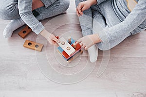 Children play with a toy designer on the floor of the children`s room. Two kids playing with colorful blocks