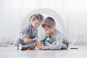 Children play with a toy designer on the floor of the children`s room. Two kids playing with colorful blocks