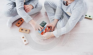 Children play with a toy designer on the floor of the children`s room. Two kids playing with colorful blocks