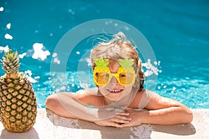 Children play in tropical resort. Child boy and best swimming pool. Cute kid relaxing on swimming pool. Summer pineapple