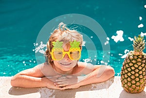 Children play in tropical resort. Child boy and best swimming pool. Cute kid relaxing on swimming pool. Summer pineapple