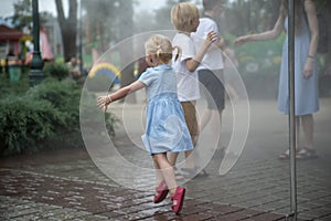 Children play under the water jets in summer park. Breeze on hot day. Walk in the park on sunny day. Playground