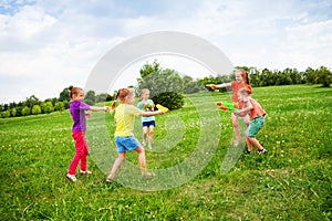 Children play with water guns on a meadow