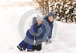 Children play in the winter outdoors with snow. Happy brother and sister together