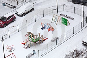 Children playground in winter season, equipment covered with snow, view from above