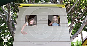 Children playhouse and little girls waving