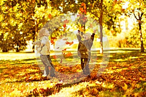 Children playing with autumn fallen leaves in park photo