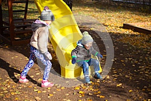 Children playing with autumn fallen leaves in park