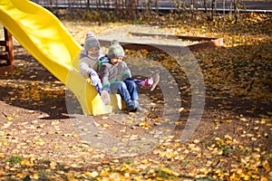 Children playing with autumn fallen leaves in park