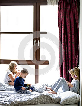 Children playing in bed with their tablets and phones
