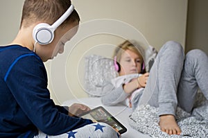 Children playing in bed with their tablets and phones