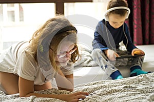 Children playing in bed with their tablets and phones