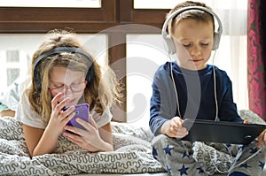 Children playing in bed with their tablets and phones