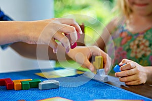 Children playing board game with colorful bricks. Closeup of hands build tower of wooden blocks, developing fine motor