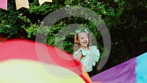 Children playing with colourful toy parachute in the garden. Slow motion.