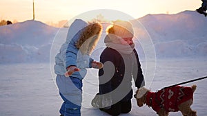Children playing with a dog in winter at sunset
