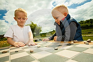 Children playing draughts or checkers board game outdoor