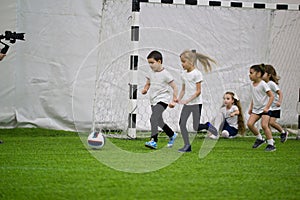 Children playing football indoors. Kids running towards the ball