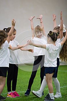 Children playing football indoors. Solid happy team of kids. Hands up