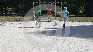 Children playing football outdoors, goal keeper hitting ball, summer activity