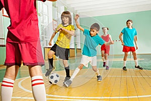 Children playing football in school gymnasium