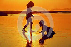 Children playing with fun on the sunset sea beach