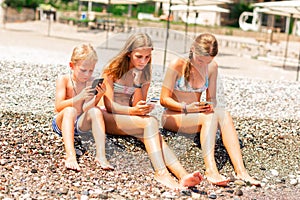 Children playing games and searching web on the telephones at the beach. Gadget dependency disorder problem for kids during