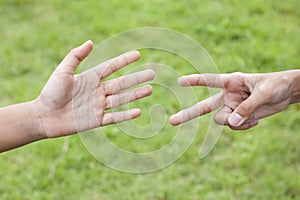 Children are playing a hand game rock paper scissors, Roshambo or RPS  in the garden.