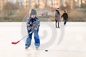 Children, playing hockey and skating in the park on frozen lake, wintertime on sunset