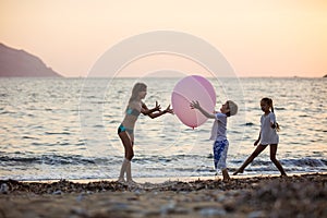 Children playing with huge pink balloon on beach
