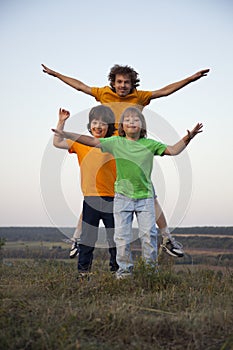 Children playing jumping on summer sunset meadow silhouetted