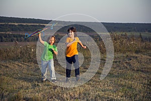 Children playing kite on summer sunset meadow