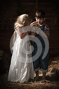 Children playing with a kitten in the barn