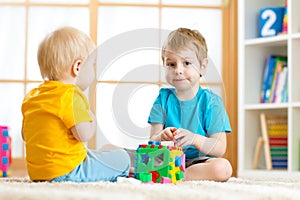Children playing with logical educational toys, arranging and sorting shapes or sizes
