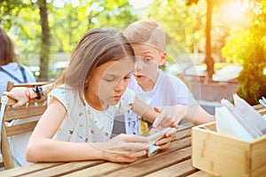 Children playing with mobile phone at terrace - Portrait of positive kids having fun together with smart phone