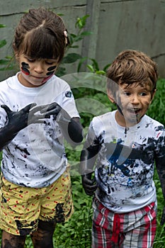 Children playing in mud, dirty cloth, messy face and hands in mud. Stains on clothes.
