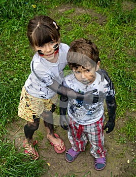 Children playing in mud, dirty cloth, messy face and hands in mud. Stains on clothes.