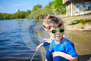 Children playing outdoors in nature: sitting on lake or river sh