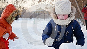 Children playing outdoors in winter. The child builds a wall of snow stones