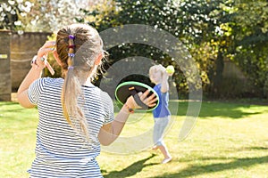 Children playing outside a brother and sister play a ball game in a garden