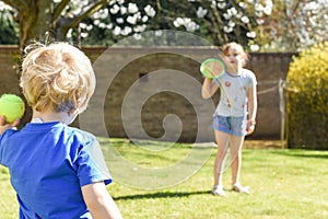 Children playing outside a brother and sister play a ball game in a garden